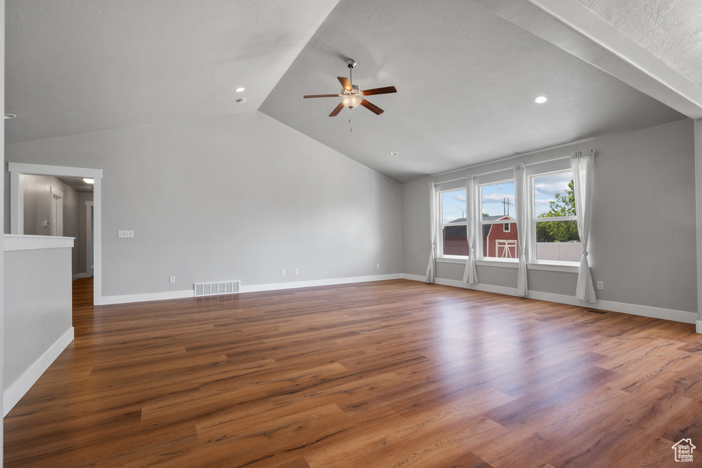 Unfurnished living room with ceiling fan, vaulted ceiling, wood finished floors, baseboards, and recessed lighting
