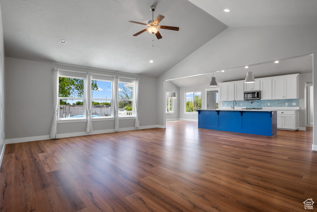 Unfurnished living room with a ceiling fan, high vaulted ceiling, a sink, dark wood-style floors, and recessed lighting