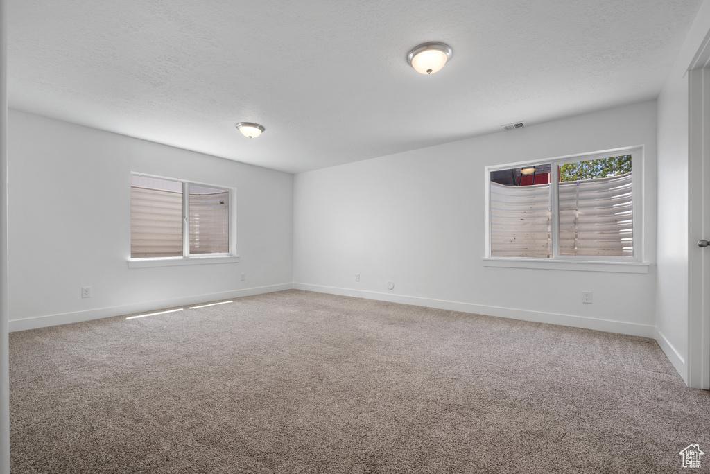 Carpeted spare room featuring baseboards and a textured ceiling