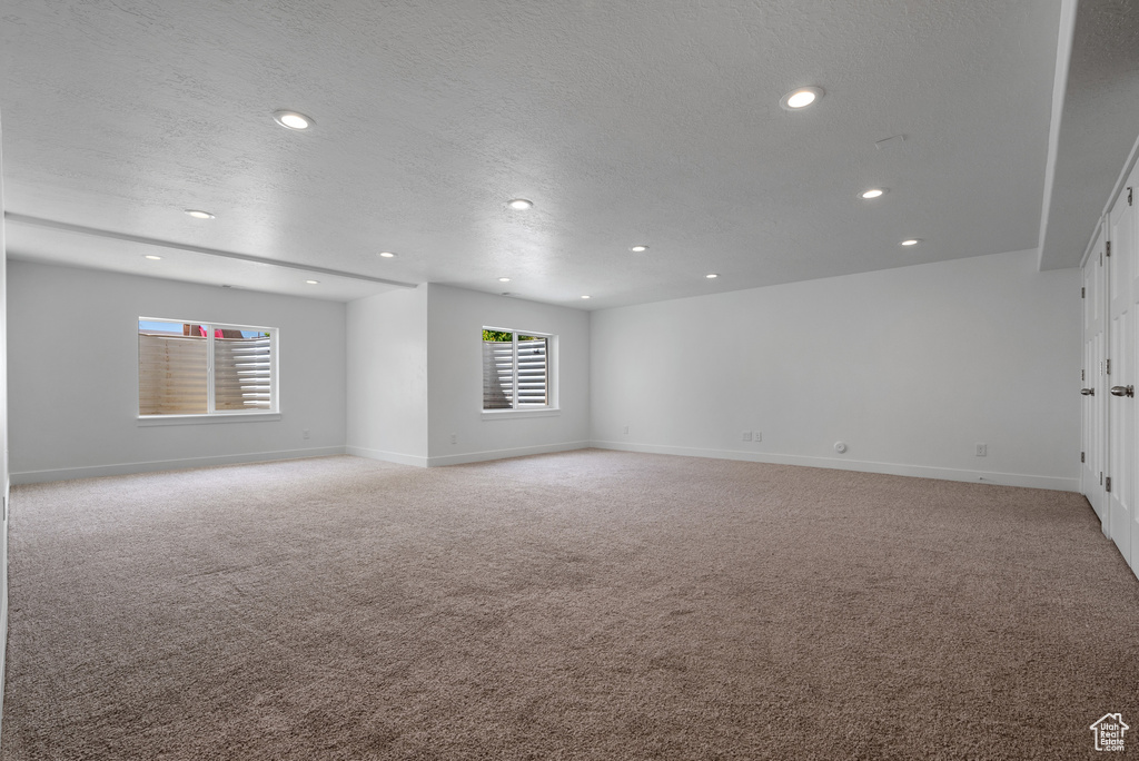 Unfurnished room featuring light carpet, recessed lighting, baseboards, and a textured ceiling