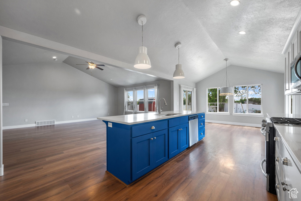 Kitchen featuring blue cabinets, appliances with stainless steel finishes, vaulted ceiling, a sink, and open floor plan