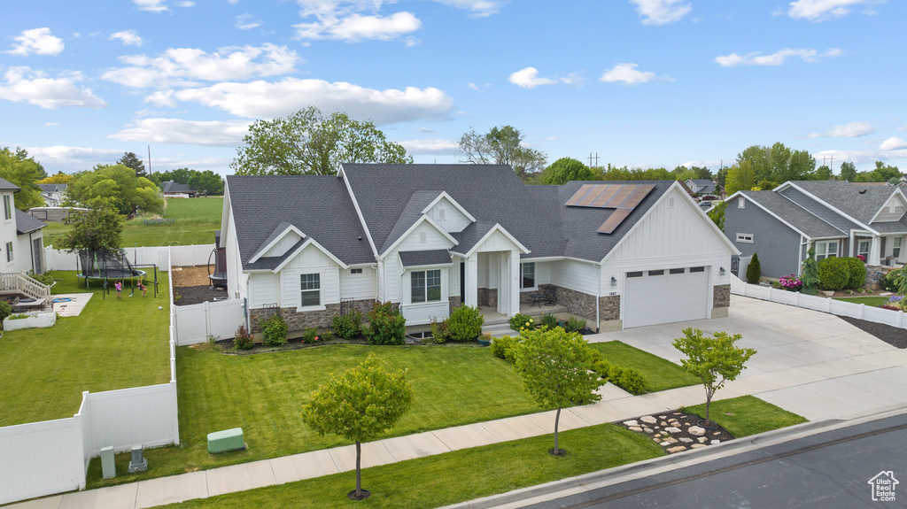View of front of house with stone siding, board and batten siding, concrete driveway, roof mounted solar panels, and a garage