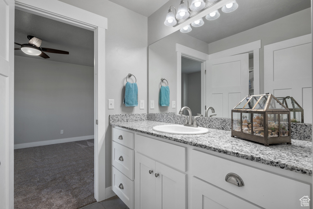 Bathroom with vanity, a ceiling fan, and baseboards