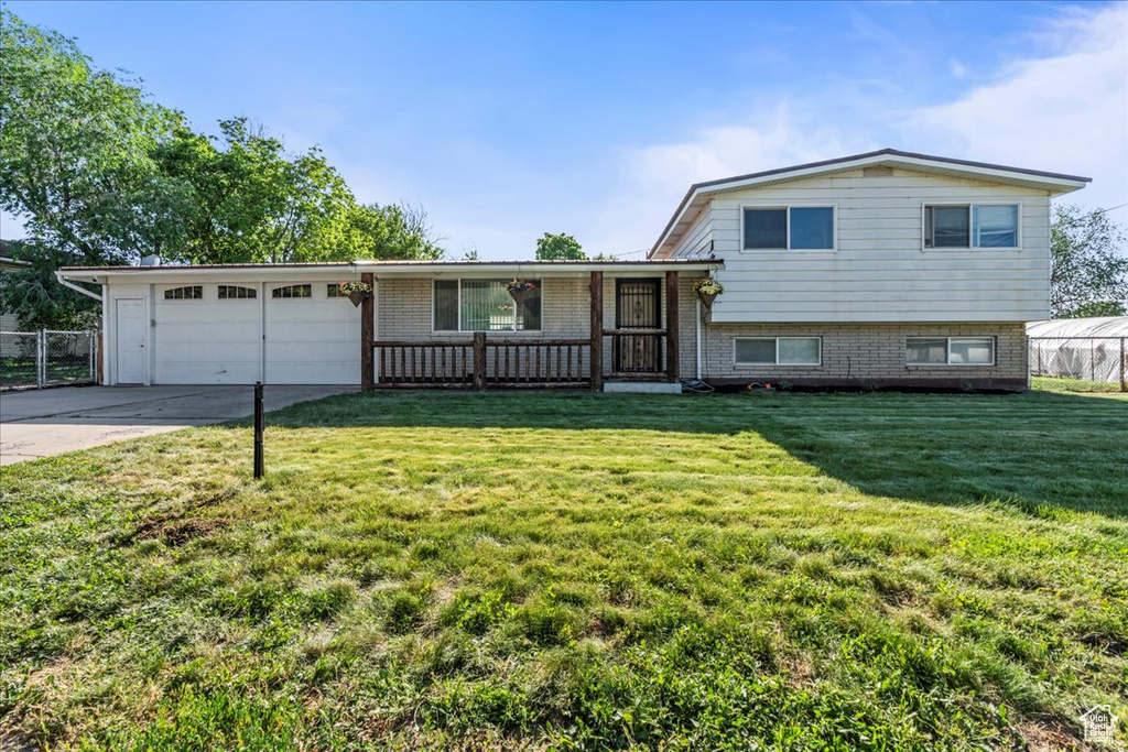 Split level home featuring an attached garage, brick siding, driveway, and a porch