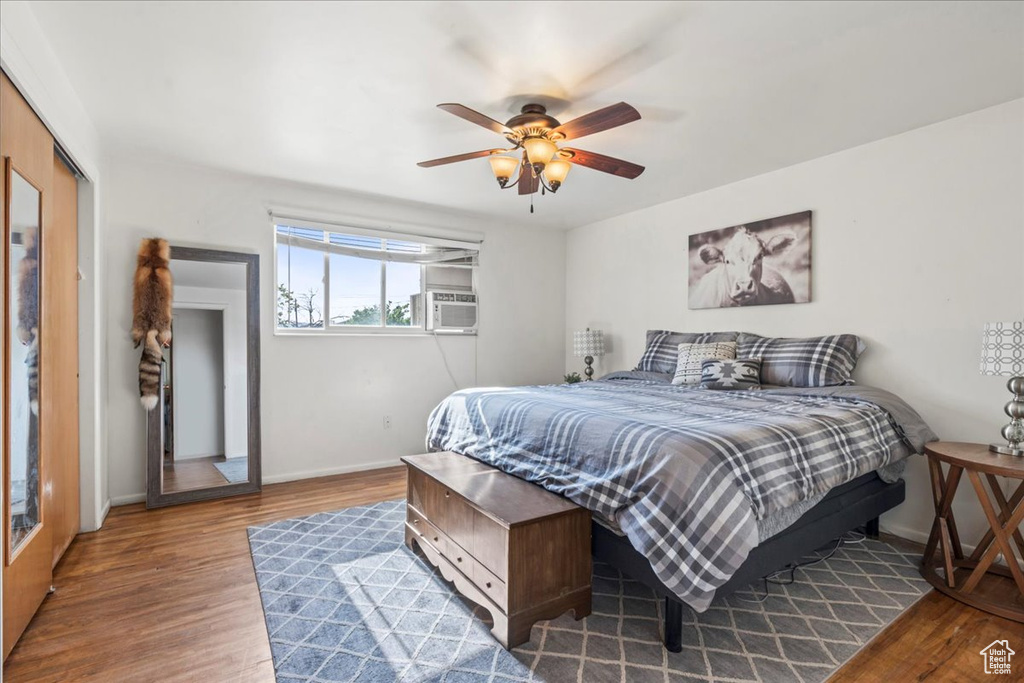 Bedroom featuring wood finished floors, baseboards, cooling unit, ceiling fan, and a closet