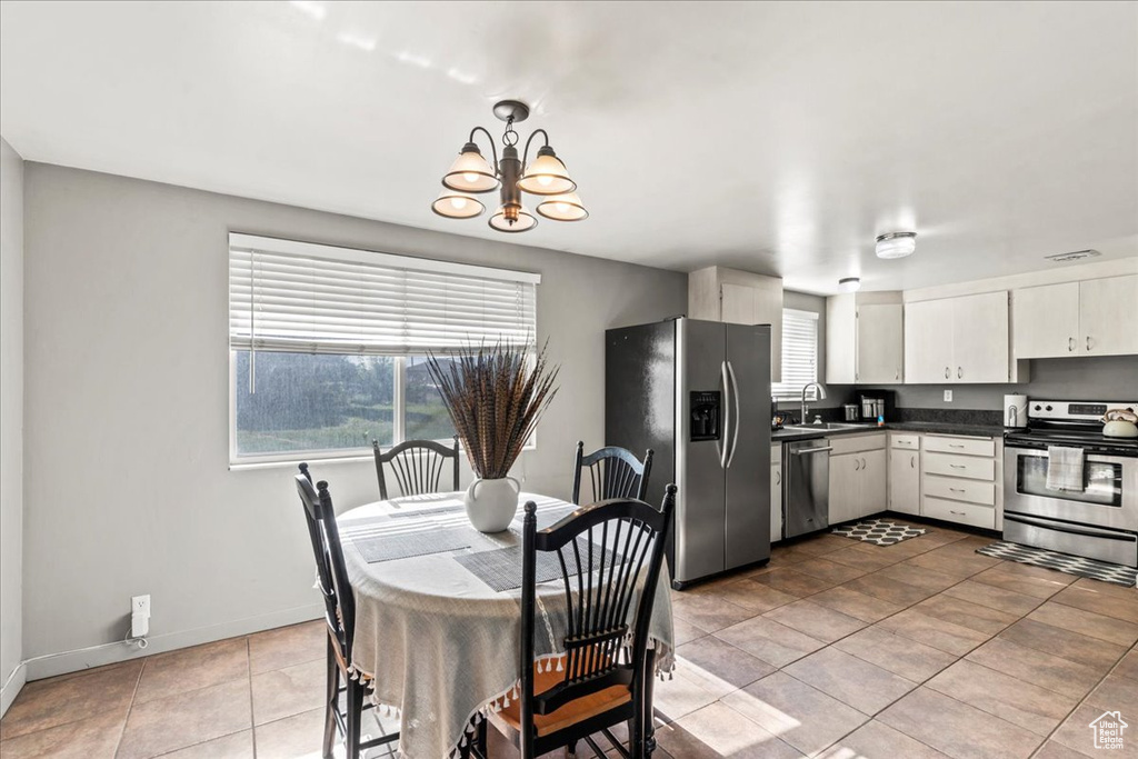 Tiled dining area with a sink, a chandelier, and baseboards