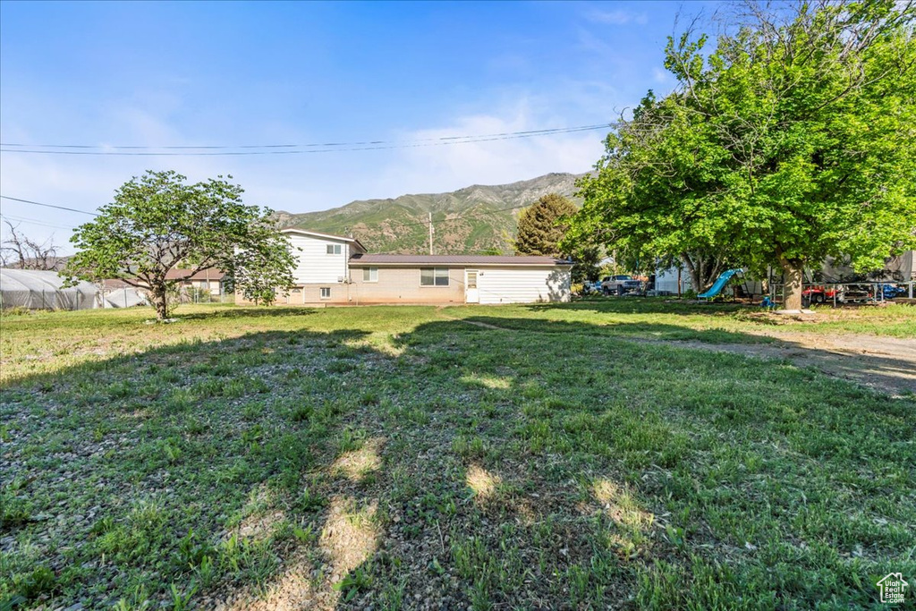 View of grassy yard with a mountain view and a playground