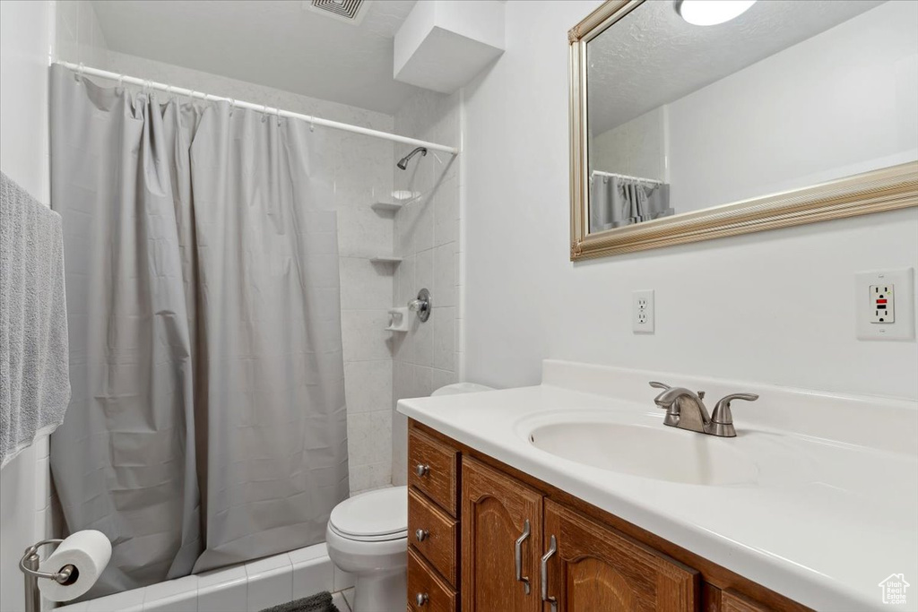 Full bathroom with toilet, vanity, and a shower with curtain