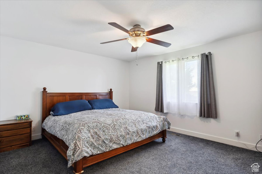 Carpeted bedroom featuring a ceiling fan and baseboards
