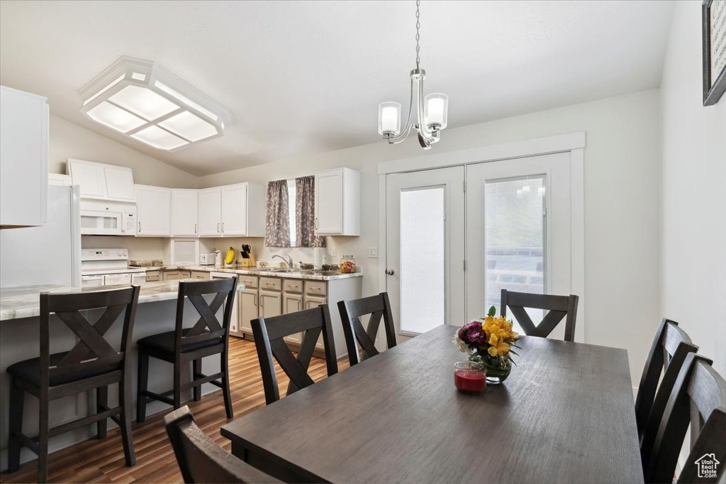 Dining room with a chandelier, wood finished floors, and vaulted ceiling