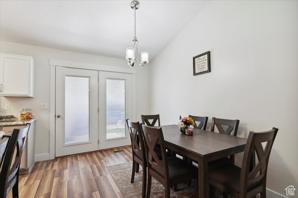 Dining room with light wood-type flooring, a chandelier, and baseboards