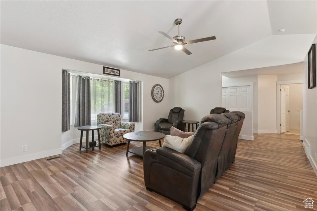 Living room with vaulted ceiling, a ceiling fan, wood finished floors, and baseboards