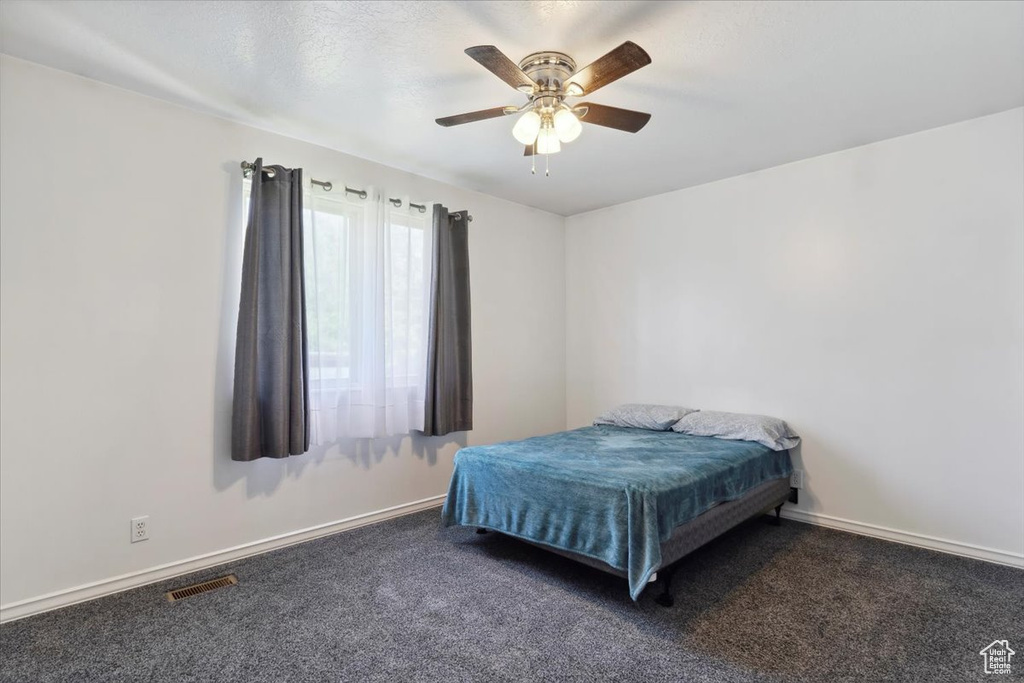 Carpeted bedroom with ceiling fan and baseboards