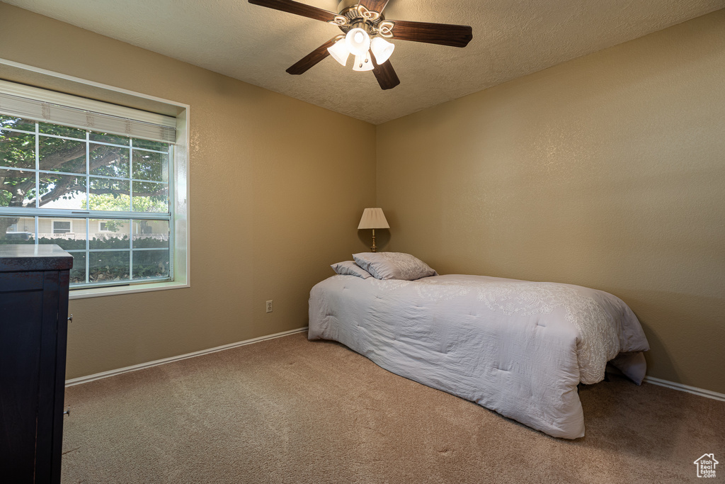Carpeted bedroom featuring baseboards, a ceiling fan, and a textured ceiling