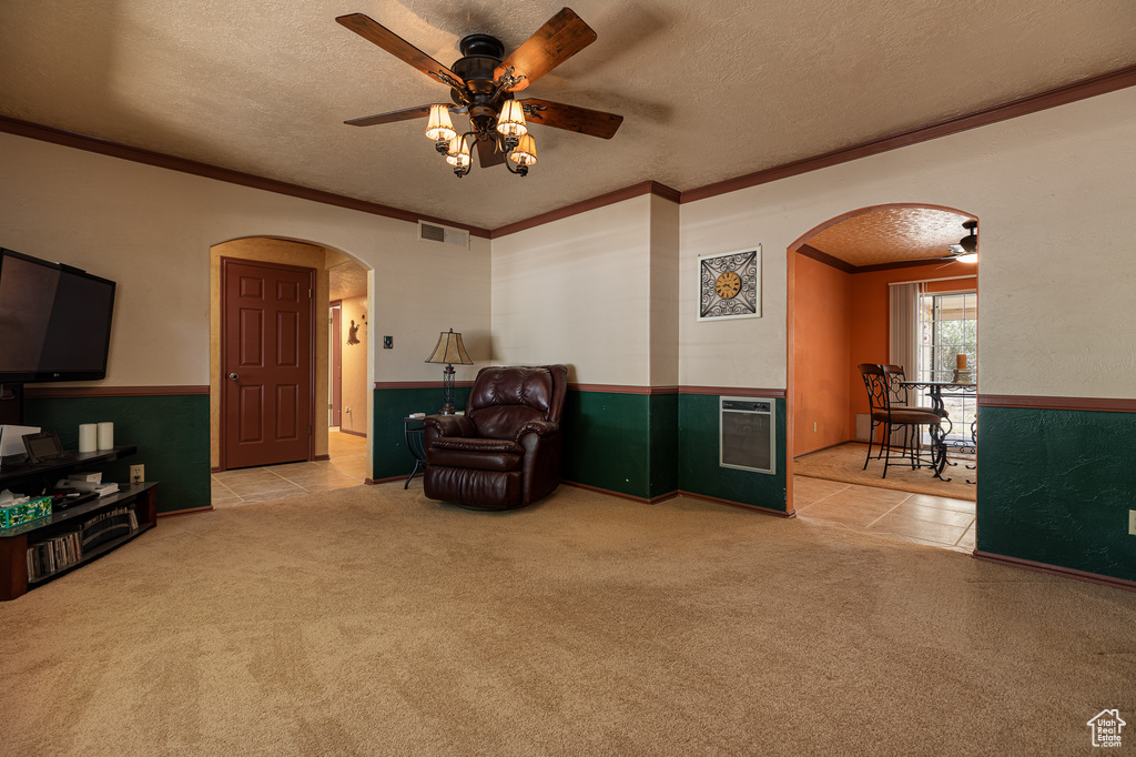 Sitting room featuring arched walkways, ornamental molding, ceiling fan, carpet floors, and a textured ceiling