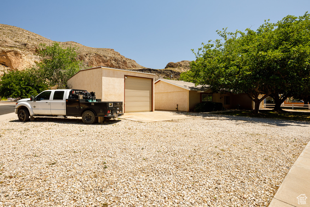 View of property exterior with a mountain view, concrete driveway, stucco siding, and a detached garage