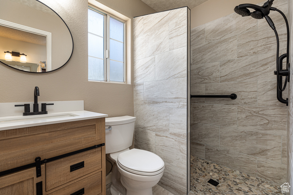 Full bath with vanity, toilet, and a tile shower