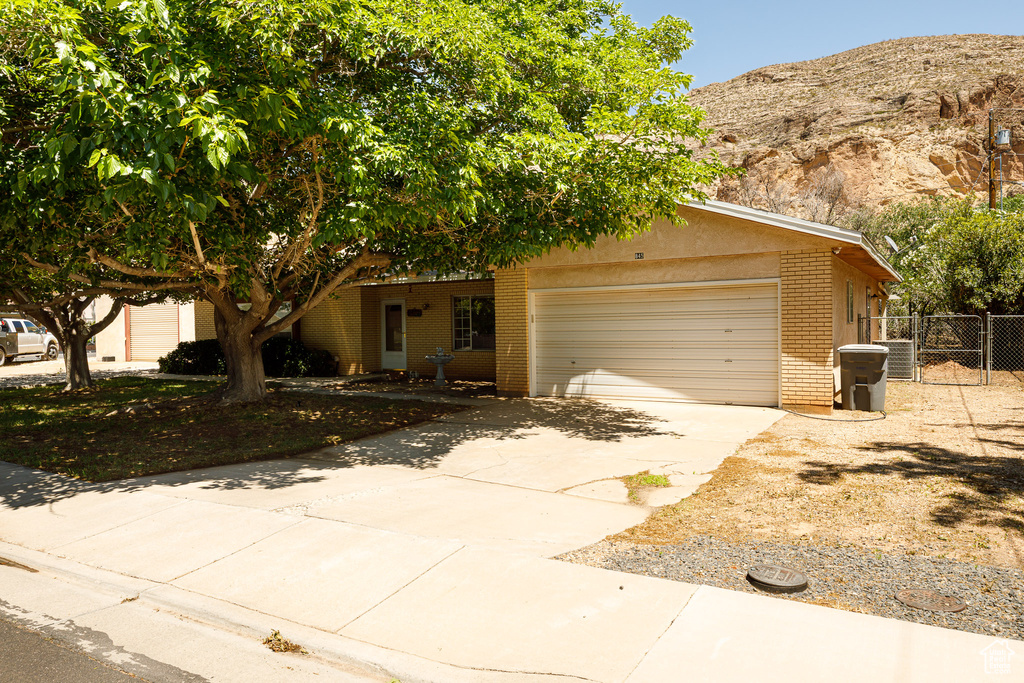 View of front facade featuring brick siding, a garage, driveway, a mountain view, and a gate