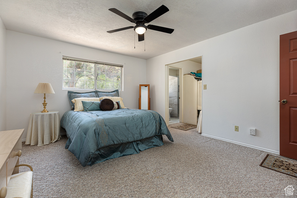 Bedroom with carpet floors, a ceiling fan, a textured ceiling, baseboards, and ensuite bath