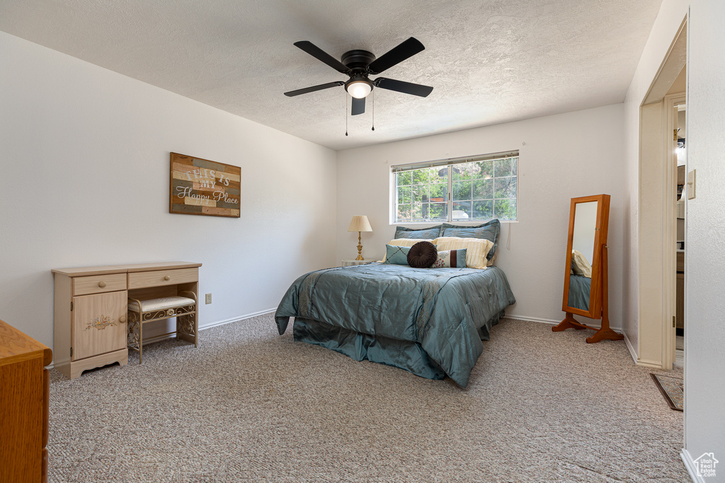 Carpeted bedroom with a textured ceiling, baseboards, and ceiling fan