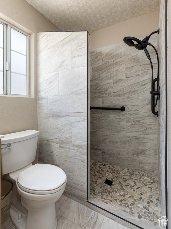 Full bathroom featuring toilet, a tile shower, and a textured ceiling