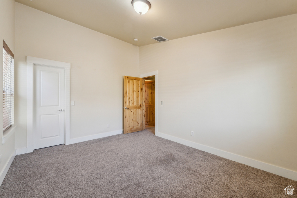 Unfurnished bedroom with carpet flooring, baseboards, and a towering ceiling