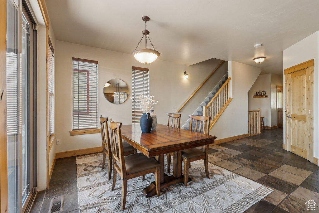 Dining space with baseboards, stairs, and dark stone finish floors