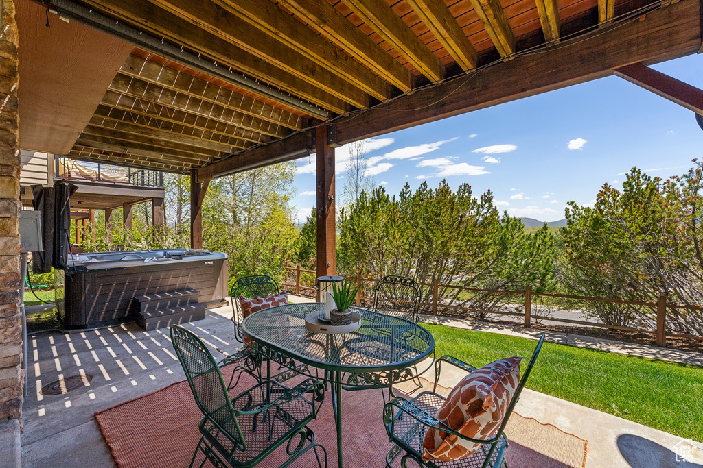 Fenced backyard with a hot tub, outdoor dining space, and a patio