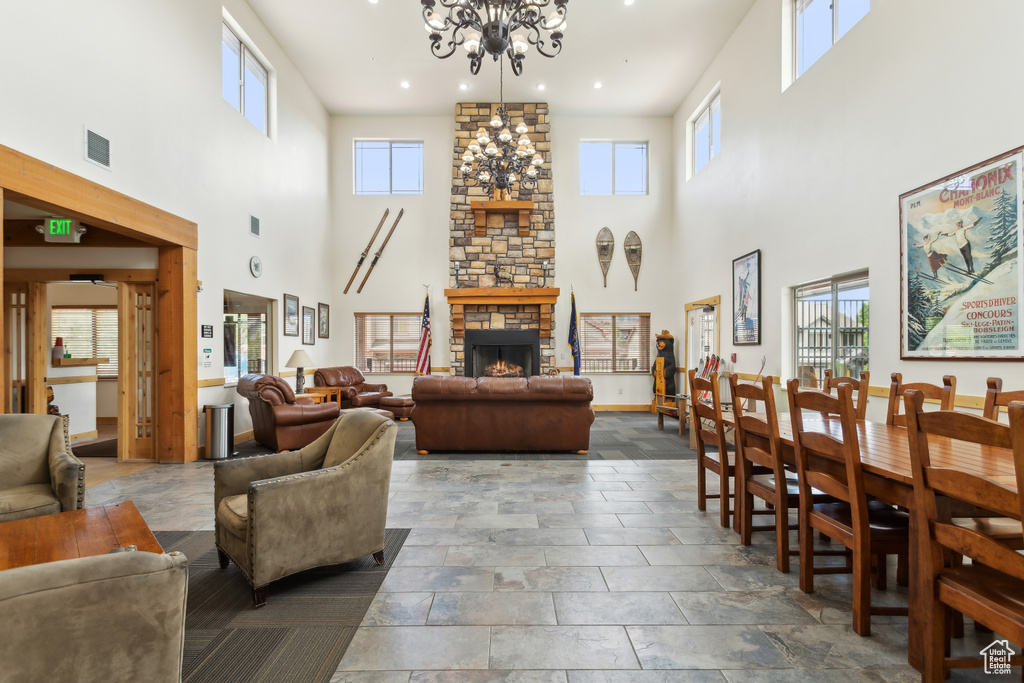 Living area with a towering ceiling, a chandelier, a stone fireplace, and recessed lighting