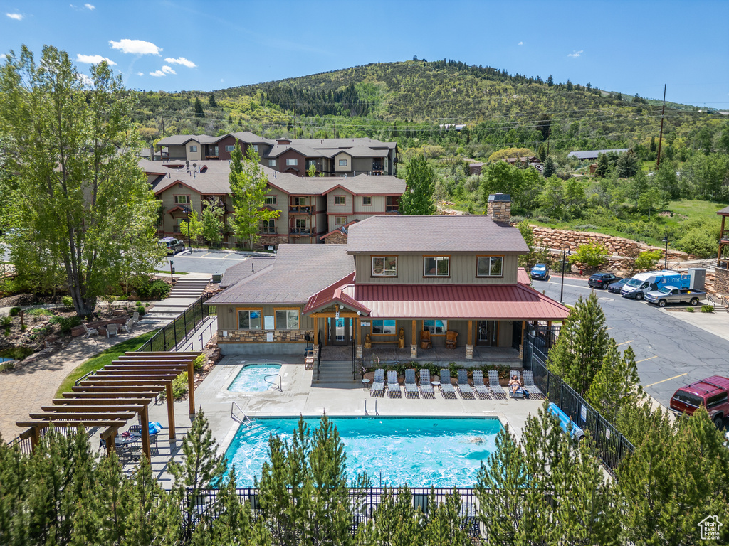 Back of property featuring a chimney, a fenced backyard, a mountain view, a community pool, and a patio area