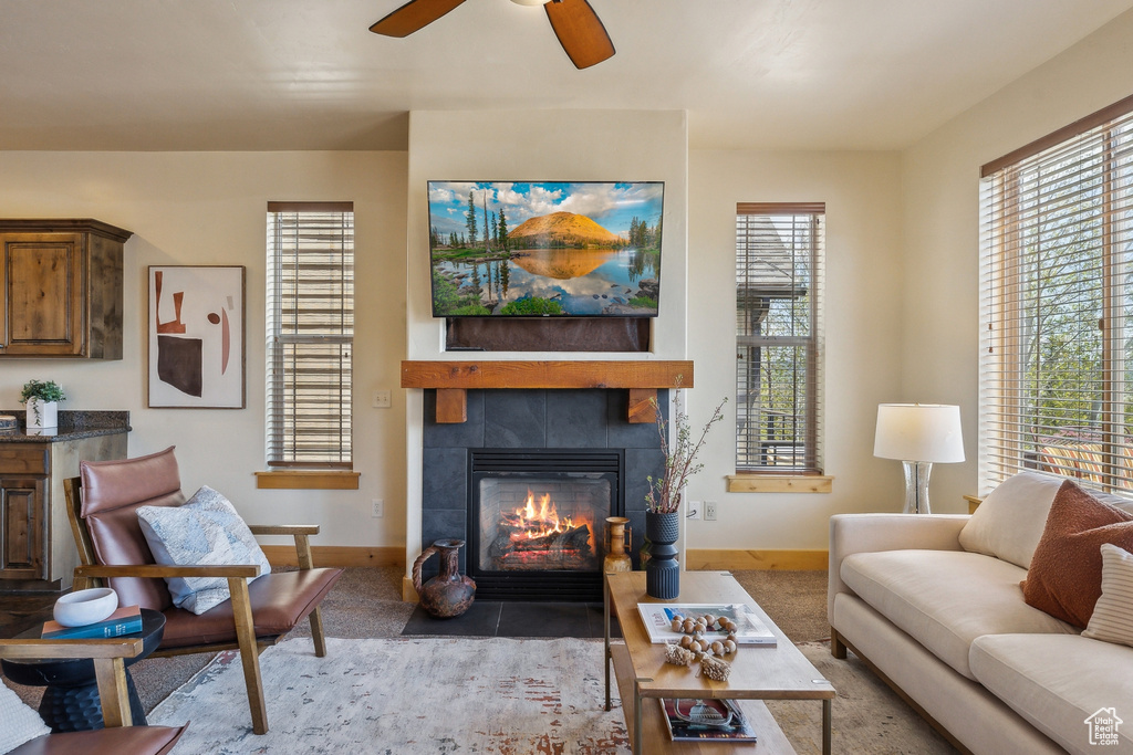 Living room featuring baseboards, a tiled fireplace, and a ceiling fan