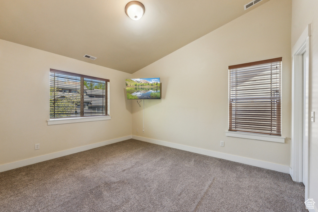 Spare room with carpet flooring, vaulted ceiling, and baseboards