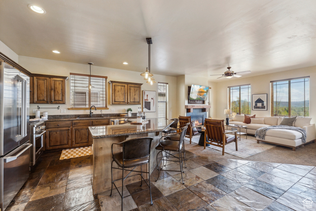 Kitchen with stainless steel appliances, a center island, a breakfast bar area, a sink, and stone tile flooring