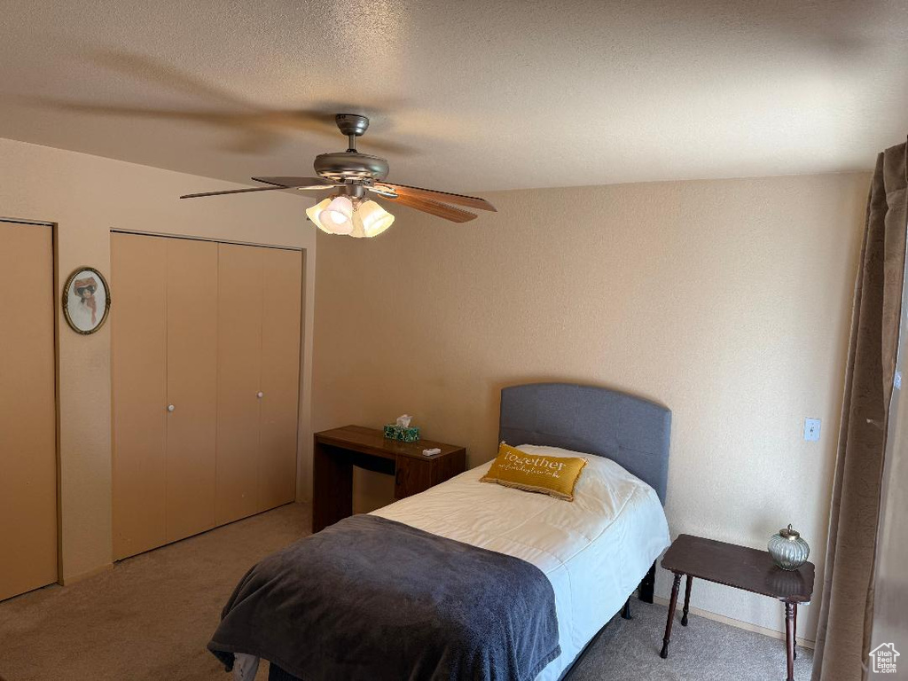 Carpeted bedroom featuring ceiling fan and multiple closets