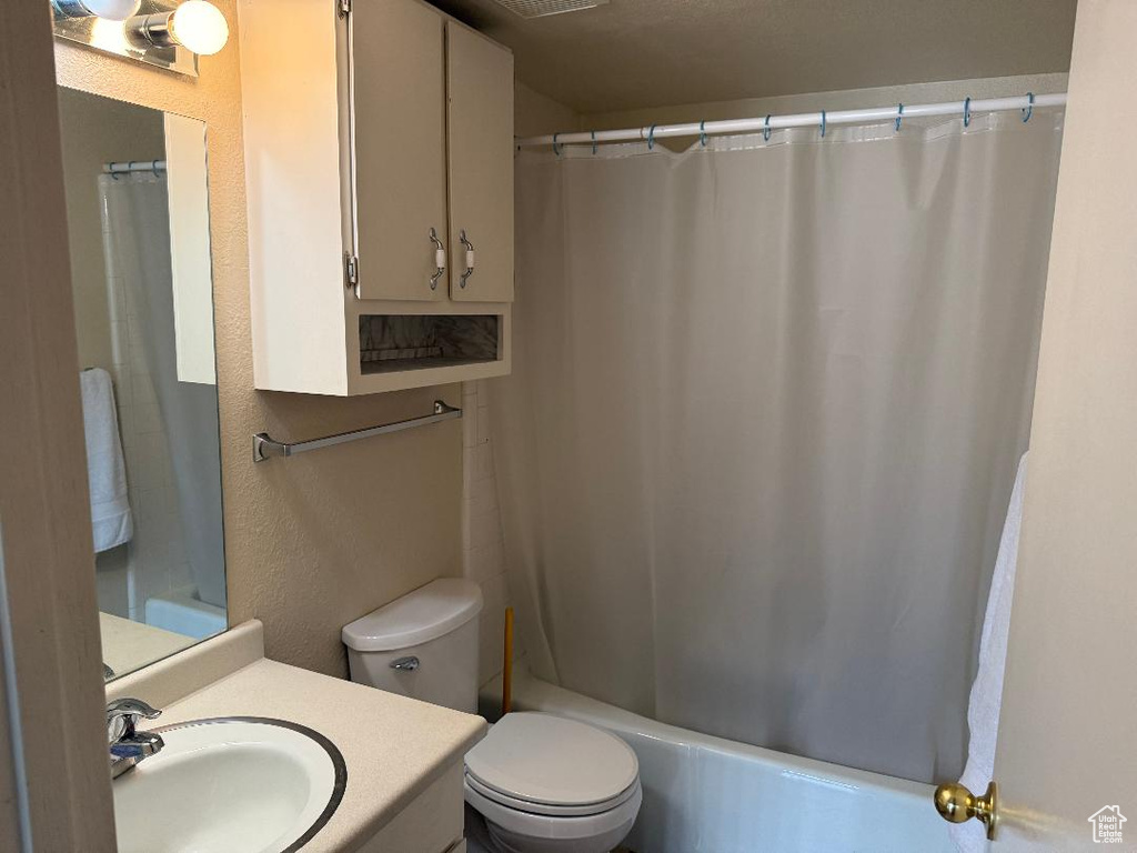 Bathroom featuring vanity, toilet, and shower / tub combo with curtain