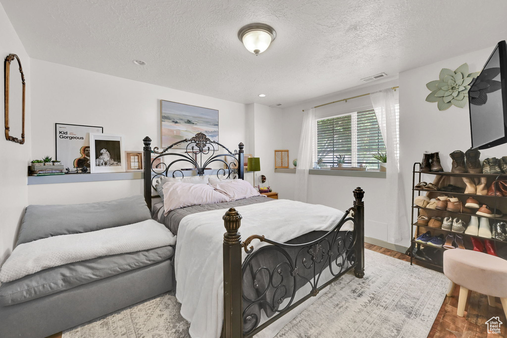 Bedroom with a textured ceiling and wood finished floors
