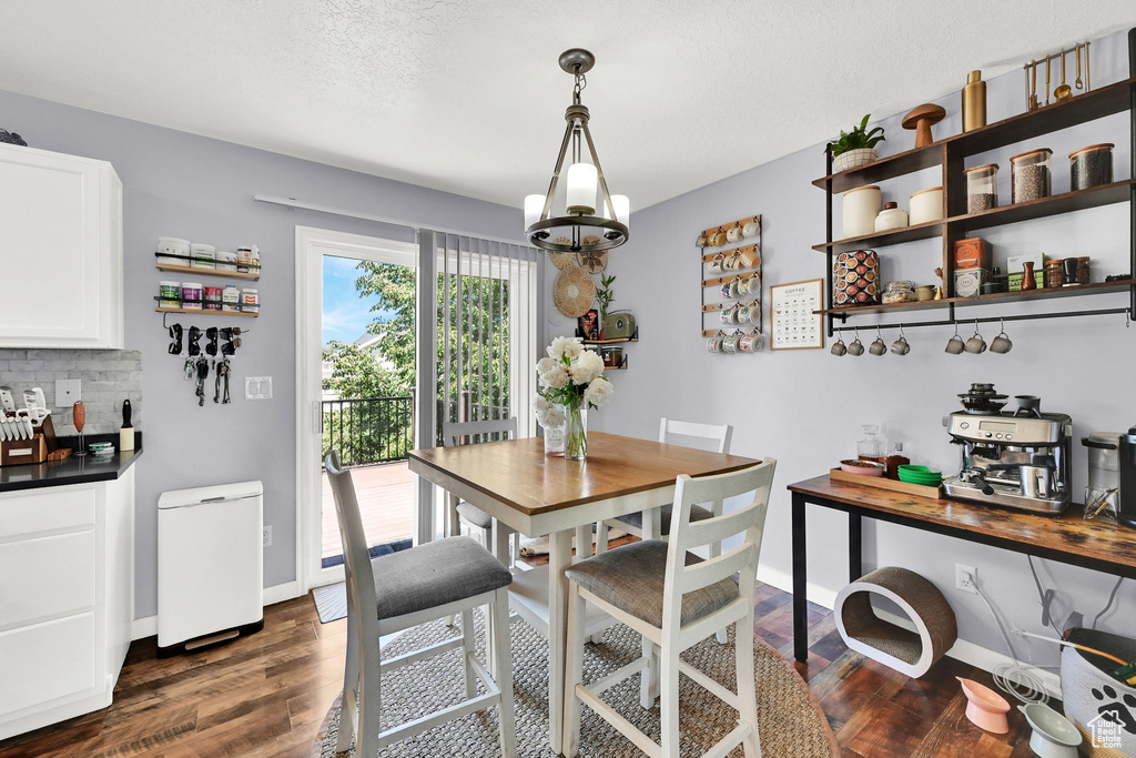Dining area featuring dark wood-style floors, baseboards, and a chandelier