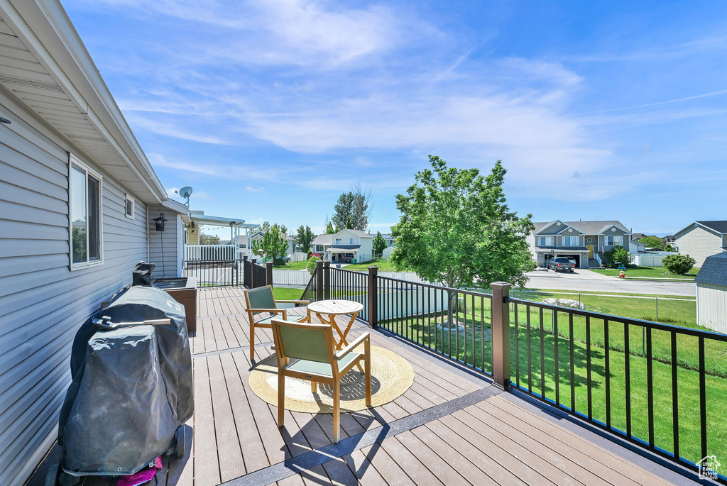 Wooden deck with a residential view, a lawn, and grilling area