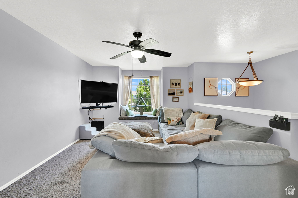 Carpeted living room featuring baseboards and a ceiling fan