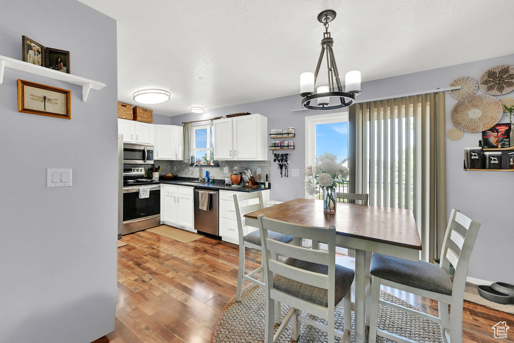 Kitchen with stainless steel appliances, plenty of natural light, a chandelier, and dark countertops