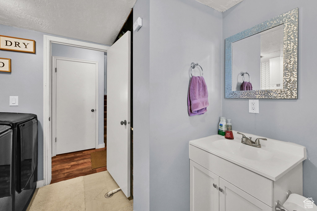 Laundry room featuring separate washer and dryer, a textured ceiling, and light wood-type flooring