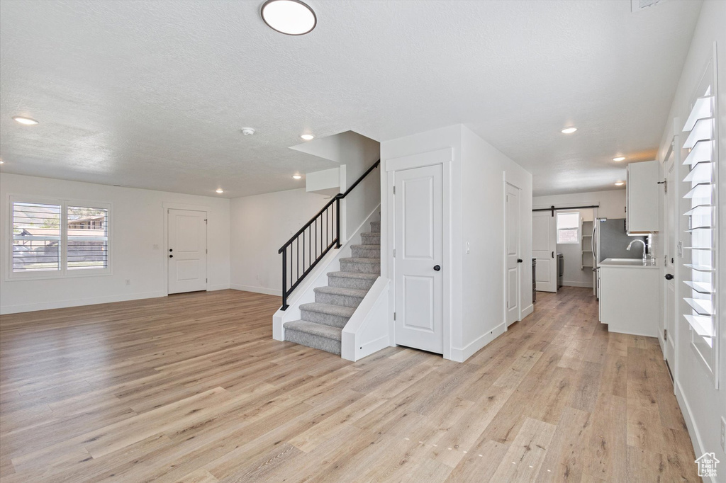Foyer entrance with light wood-style flooring, stairs, baseboards, recessed lighting, and a barn door