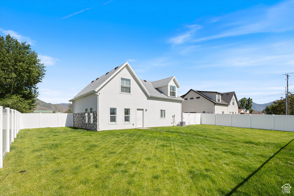 Rear view of house featuring stucco siding, stone siding, and central AC unit