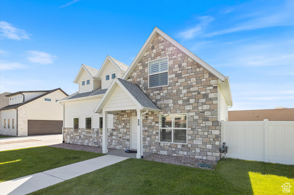 View of front of property with stone siding, driveway, and a shingled roof