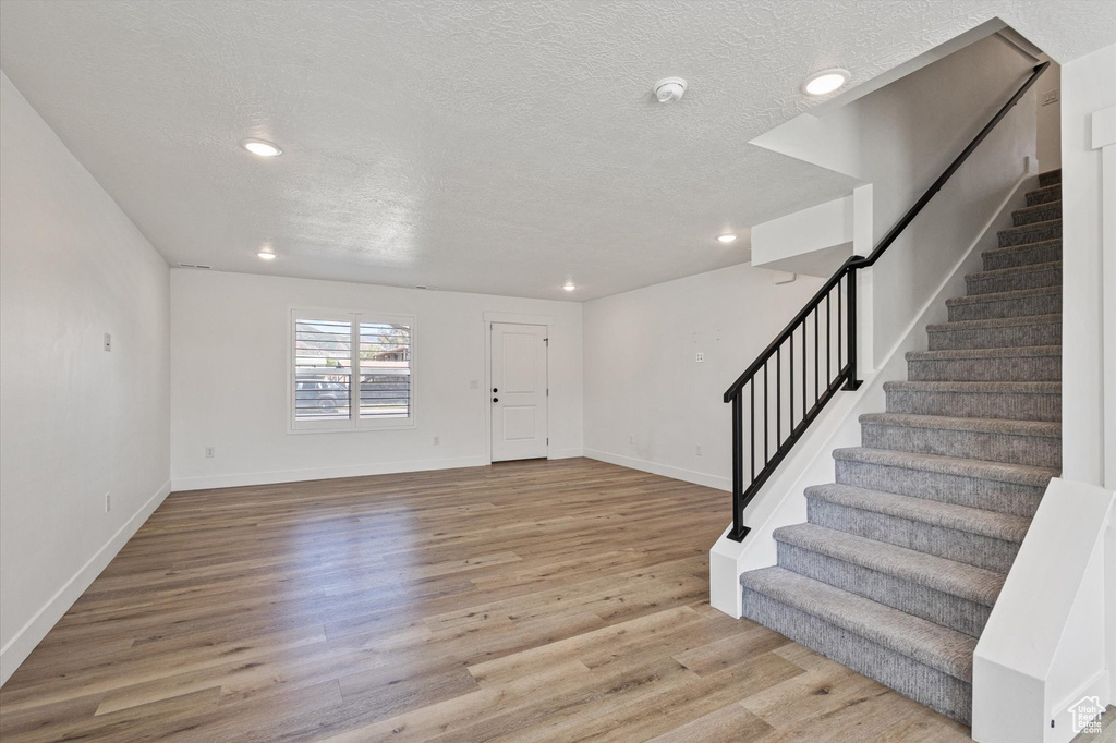 Foyer entrance with stairway, wood finished floors, recessed lighting, a textured ceiling, and baseboards