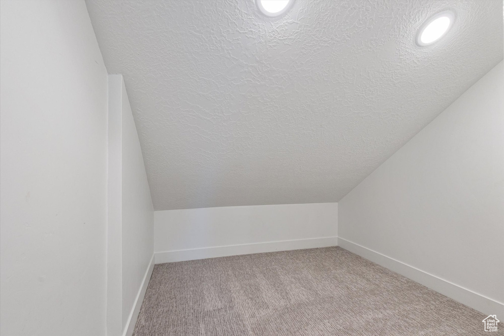 Bonus room with a textured ceiling, lofted ceiling, light colored carpet, baseboards, and recessed lighting