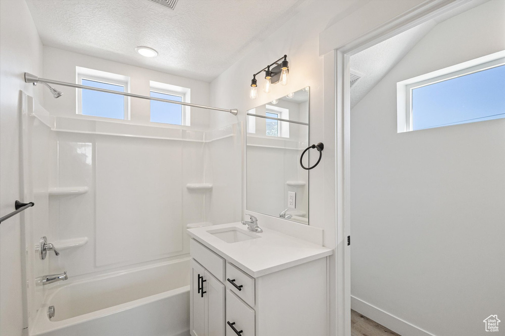 Bathroom with shower / bath combination, vanity, healthy amount of natural light, and a textured ceiling