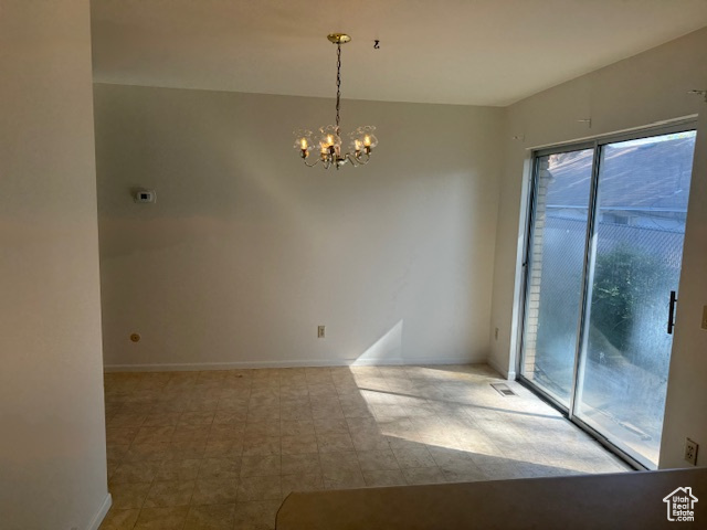 Empty room featuring a chandelier and baseboards