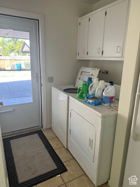 Laundry room featuring separate washer and dryer, light tile patterned flooring, and cabinet space