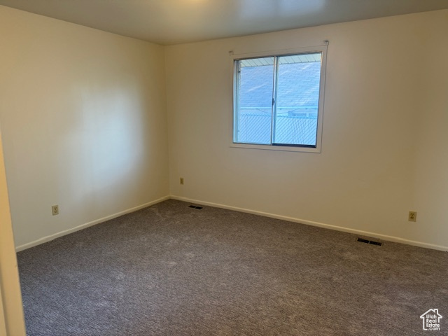 Empty room with dark carpet and baseboards